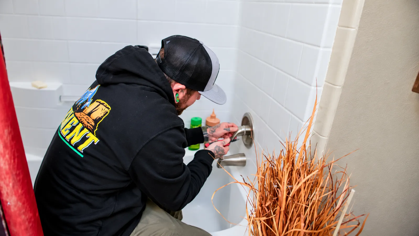 Element plumber repairing a faucet in a tiled shower in Flagstaff