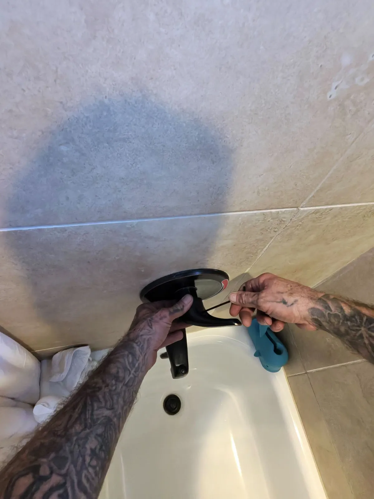 Water stain on a shower wall from a hidden leak, with the tub drain being repaired